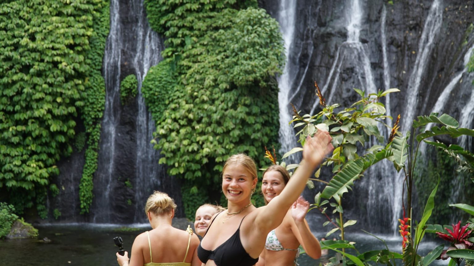 Glade rejsende ved et vandfald på Bali