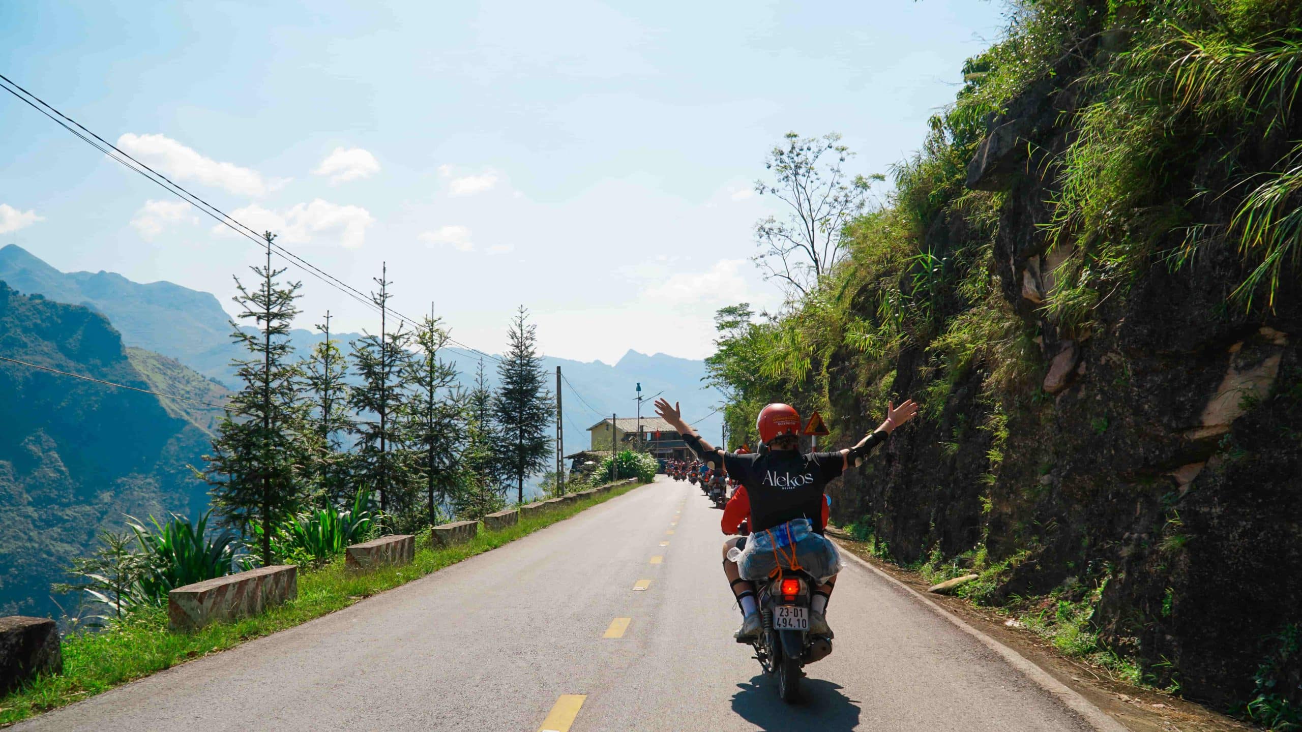 Ung rejsende kører på scooter ad en bjergvej i Vietnam