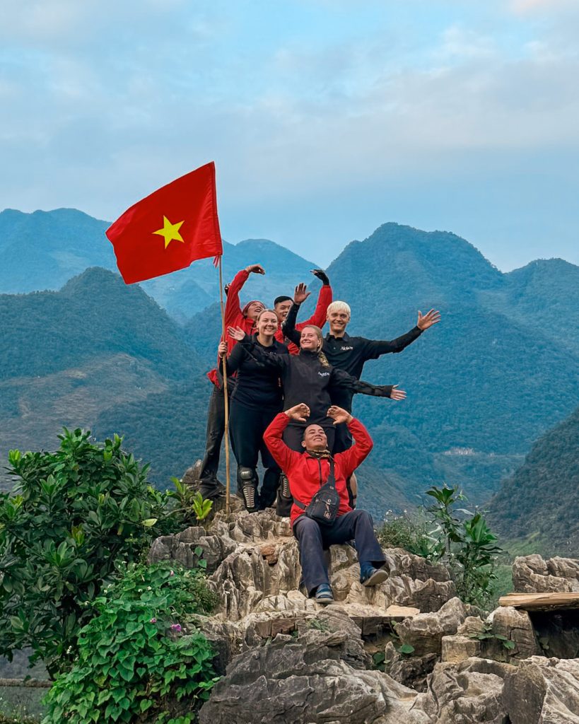 To rejsende med det vietnamesiske flag foran bjergene på Ha Giang Loop