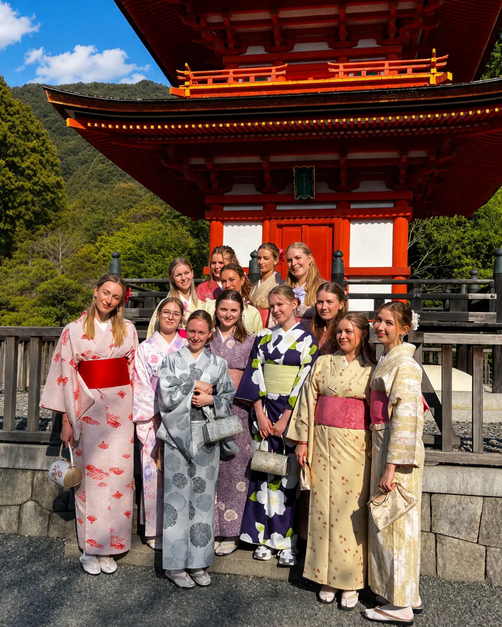 Rejsende i kimono foran et rødt tempel i Kyoto