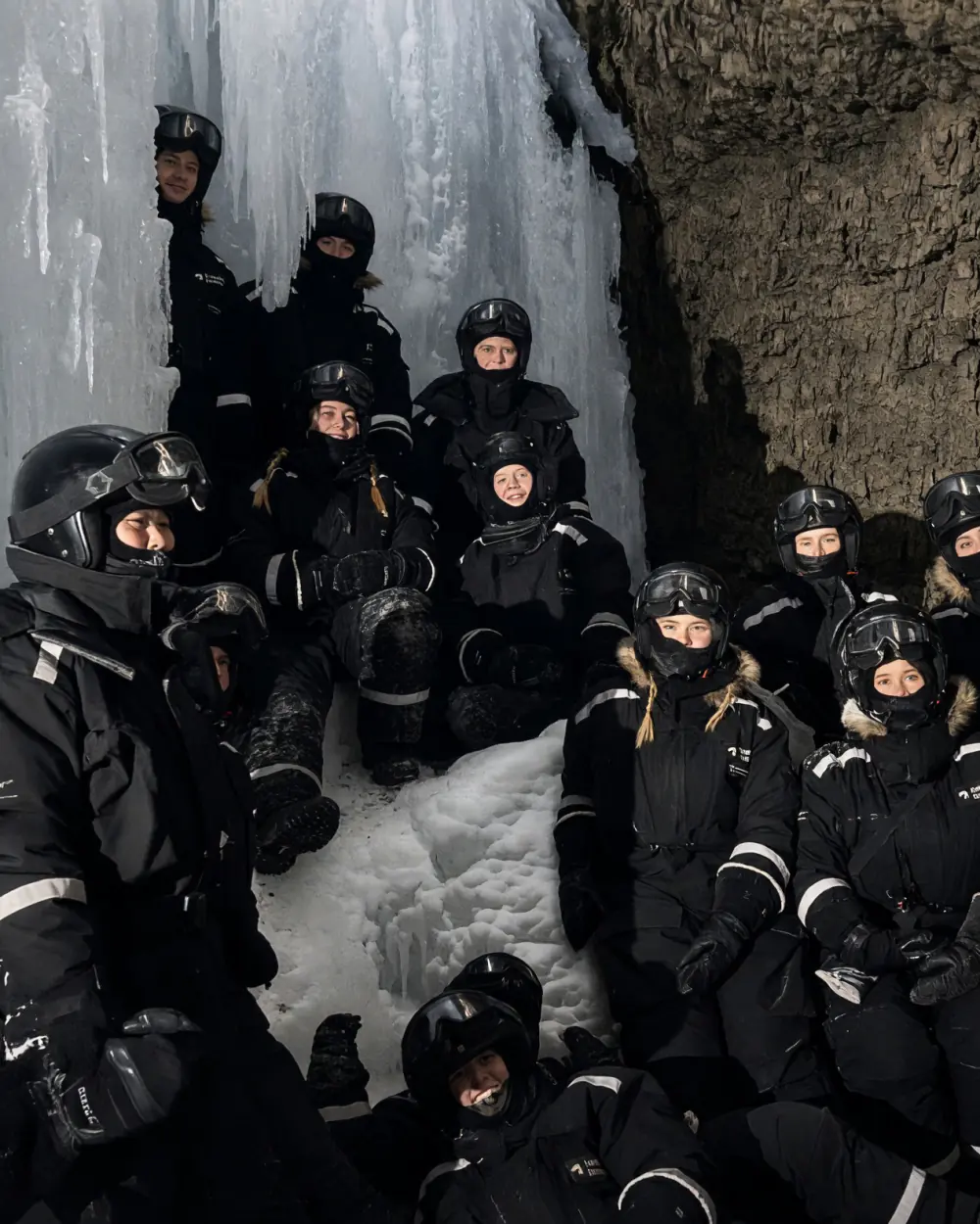 Gruppen i varme dragter og hjelme i en ishule på Svalbard
