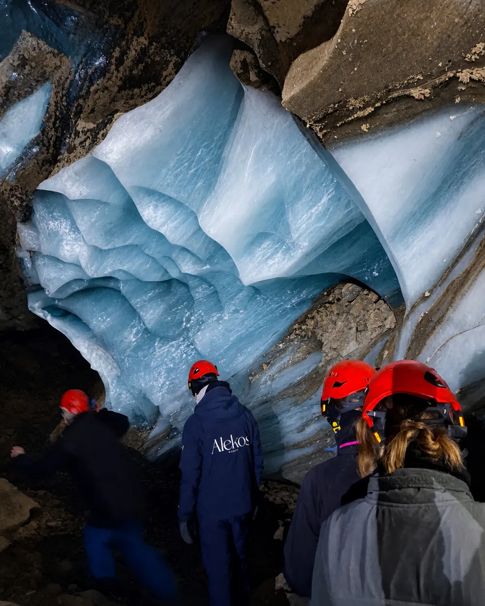 Rejsende med hjelme i en isgrotte på Svalbard