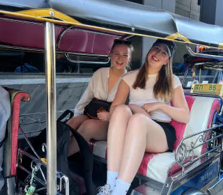 To rejsende på bagsædet af en tuk-tuk i Bangkok