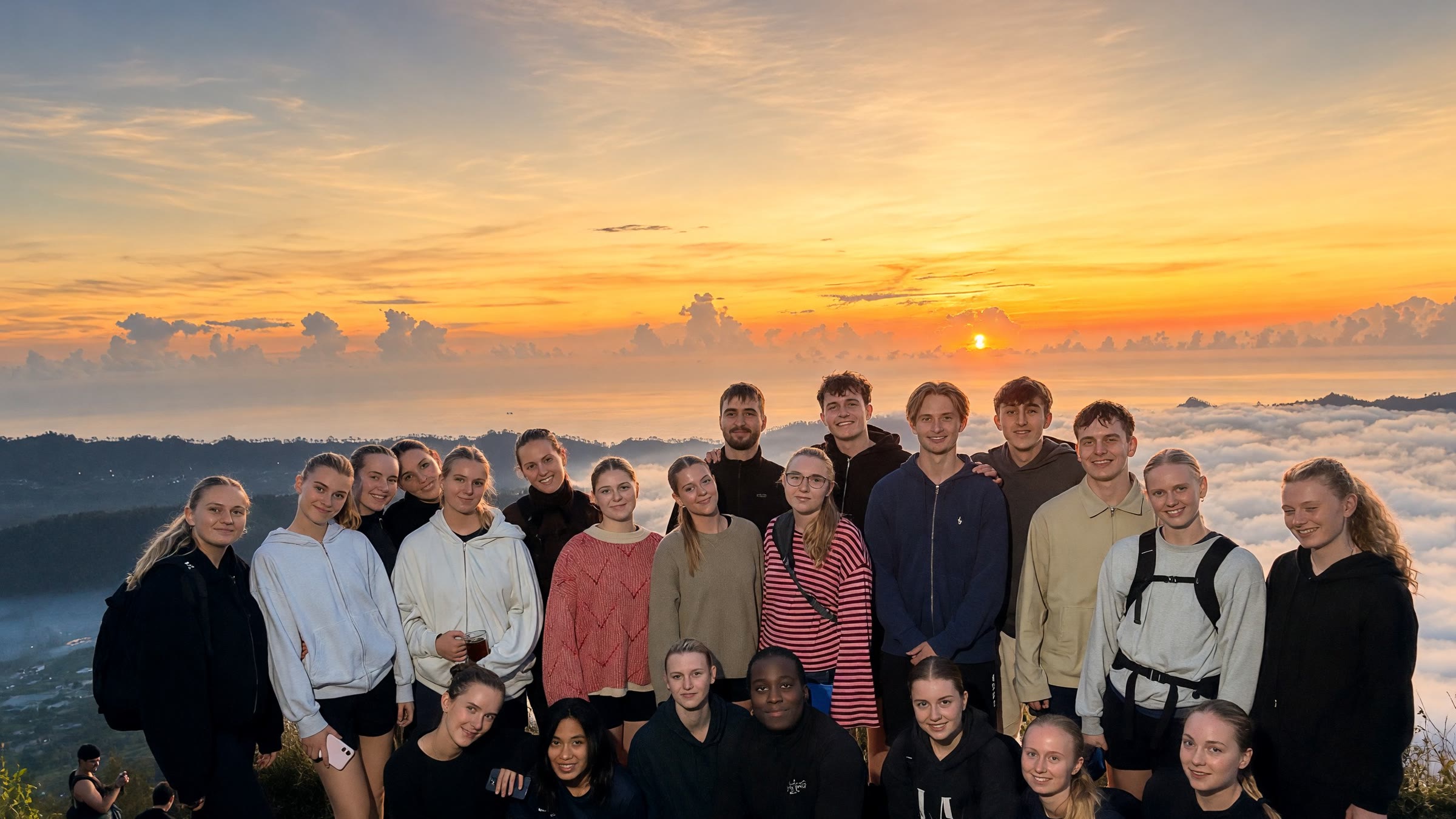 Hele holdet samlet på toppen af Mount Batur over skyerne ved solopgang
