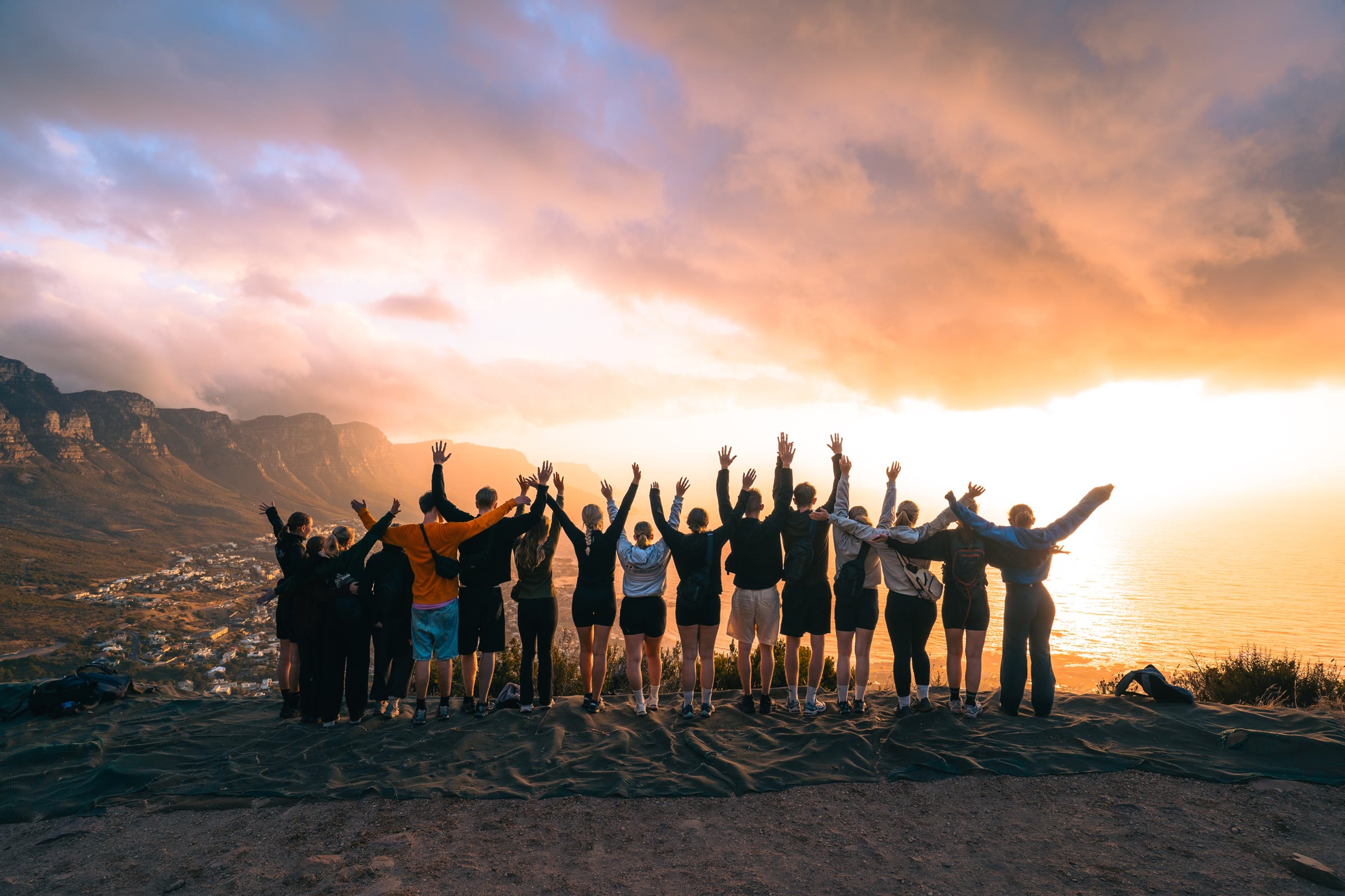 Holdet med armene i vejret på toppen af Lion's Head ved solnedgang